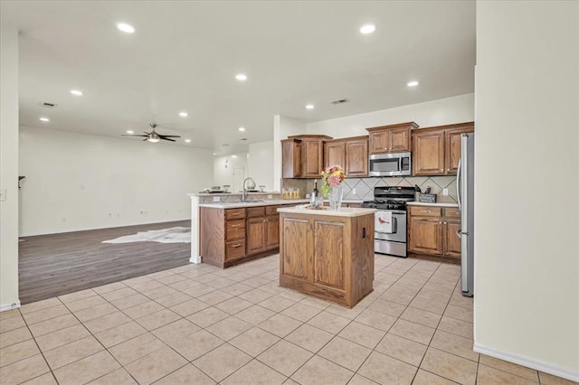 11321 NW 103rd St, Yukon, OK 73099 - kitchen featuring stainless steel appliances, brown cabinetry, open floor plan, a peninsula, and light tile patterned floors