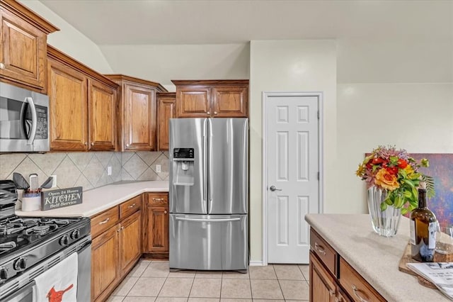 11321 NW 103rd St, Yukon, OK 73099 - kitchen featuring stainless steel appliances, brown cabinetry, and backsplash