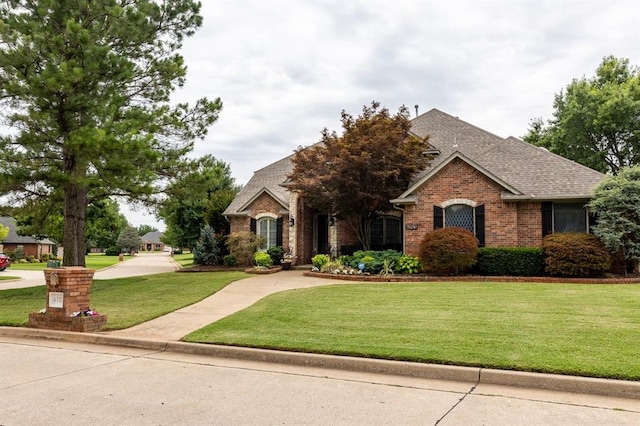 4719 W Two Lakes Ave, Norman, OK 73072 - view of front facade featuring brick siding, a front yard, and a shingled roof