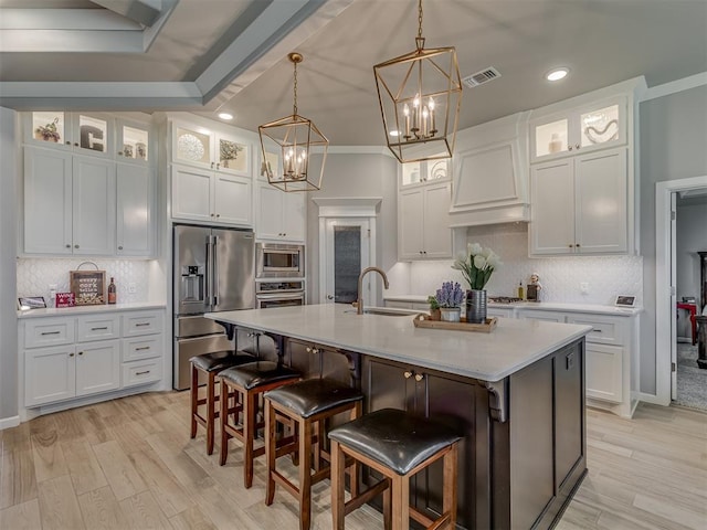 10101 NW 137th St, Yukon, OK 73099 - kitchen with appliances with stainless steel finishes, a chandelier, premium range hood, a kitchen island with sink, and white cabinets