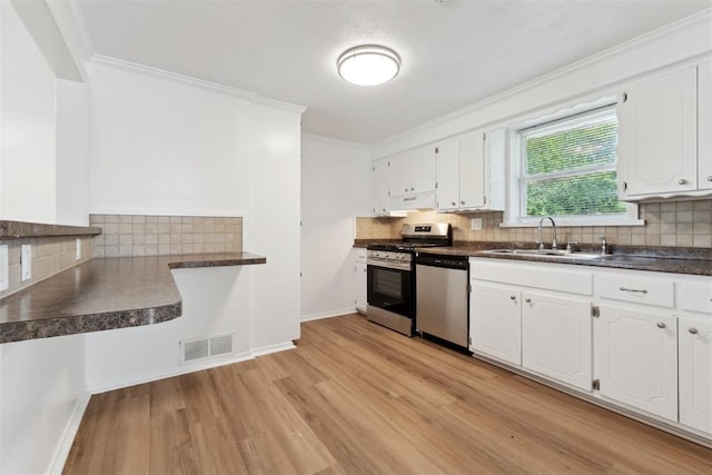 4112 SE 22nd St, Del City, OK 73115 - kitchen featuring appliances with stainless steel finishes, light wood finished floors, dark countertops, white cabinetry, and tasteful backsplash