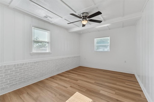 4112 SE 22nd St, Del City, OK 73115 - empty room featuring coffered ceiling, light wood finished floors, ceiling fan, brick wall, and beam ceiling