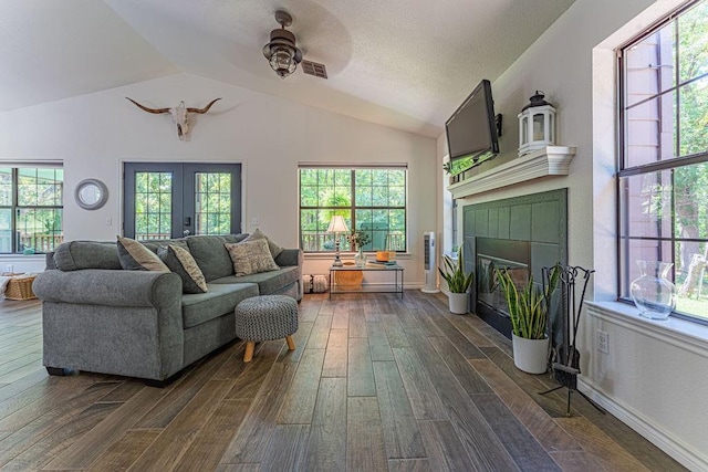 22797 N Henney Rd, Luther, OK 73054 - living room featuring a tiled fireplace, dark wood-style floors, lofted ceiling, ceiling fan, and french doors