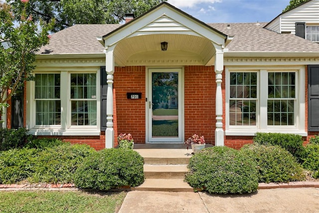 701 NW 46th St, Oklahoma City, OK 73118 - property entrance with brick siding, a chimney, a shingled roof, and a porch