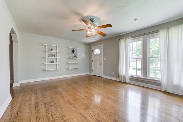 701 NW 46th St, Oklahoma City, OK 73118 - unfurnished living room featuring ceiling fan, arched walkways, built in features, and wood finished floors