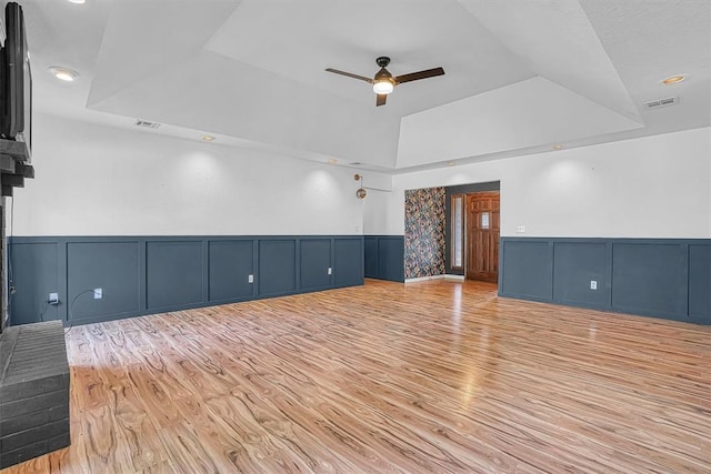3208 Quail Cir, Altus, OK 73521 - empty room featuring a tray ceiling, a decorative wall, a ceiling fan, light wood-style floors, and a wainscoted wall