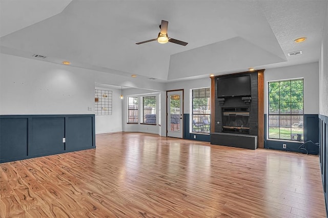 3208 Quail Cir, Altus, OK 73521 - unfurnished living room featuring a ceiling fan, a raised ceiling, light wood finished floors, a fireplace, and vaulted ceiling