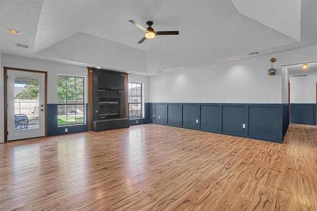 3208 Quail Cir, Altus, OK 73521 - unfurnished living room with a tray ceiling, a ceiling fan, healthy amount of natural light, light wood-type flooring, and wainscoting