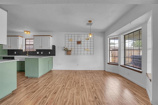 3208 Quail Cir, Altus, OK 73521 - kitchen featuring green cabinetry, light wood-type flooring, plenty of natural light, a textured ceiling, and light countertops