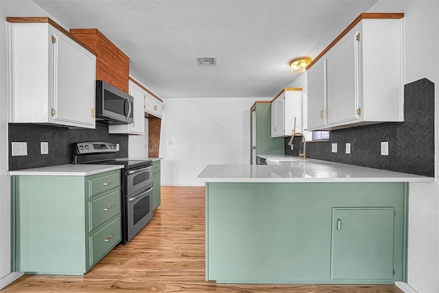 3208 Quail Cir, Altus, OK 73521 - kitchen featuring appliances with stainless steel finishes, a peninsula, backsplash, light countertops, and light wood finished floors