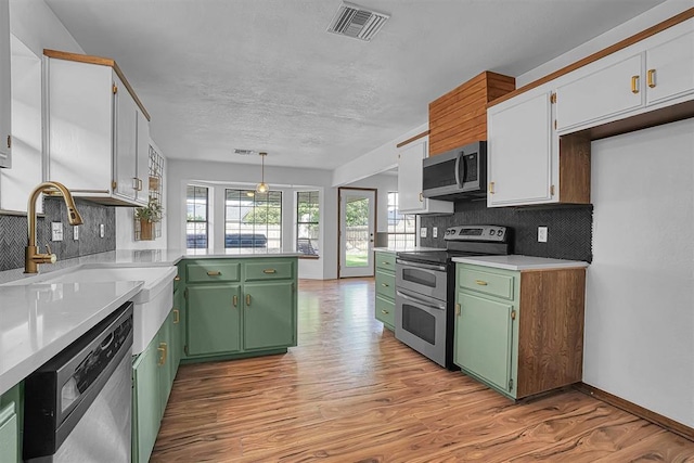 3208 Quail Cir, Altus, OK 73521 - kitchen featuring stainless steel appliances, green cabinets, light wood-style flooring, a peninsula, and light countertops