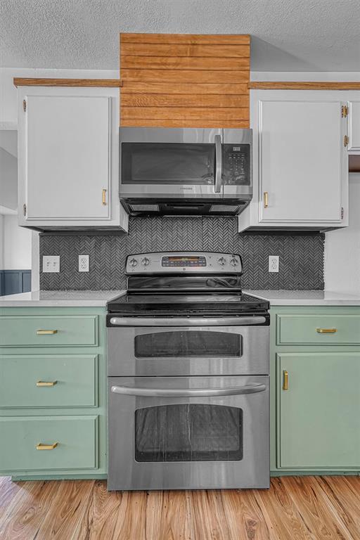 3208 Quail Cir, Altus, OK 73521 - kitchen with stainless steel appliances, green cabinets, light countertops, backsplash, and a textured ceiling