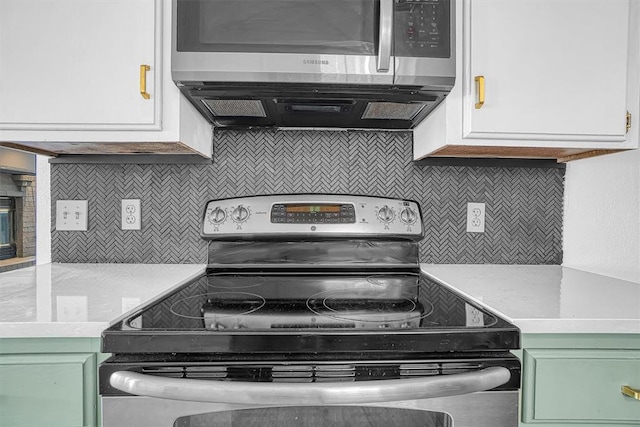 3208 Quail Cir, Altus, OK 73521 - kitchen with stainless steel appliances, green cabinetry, light countertops, and decorative backsplash