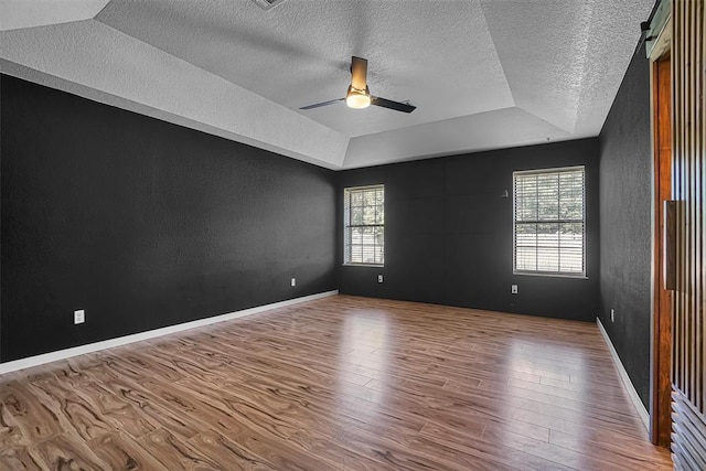 3208 Quail Cir, Altus, OK 73521 - empty room with a tray ceiling, a textured ceiling, wood finished floors, a textured wall, and a ceiling fan