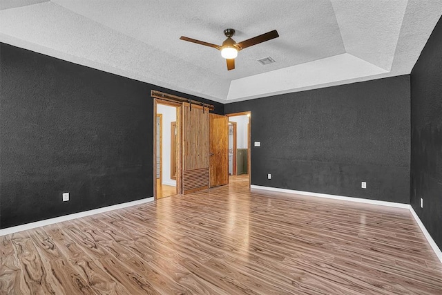 3208 Quail Cir, Altus, OK 73521 - spare room with a textured wall, wood finished floors, a textured ceiling, a raised ceiling, and ceiling fan