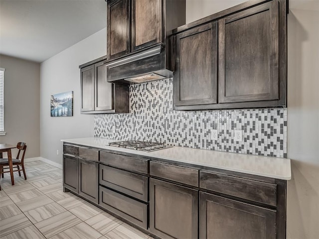 3903 Painted Bird Ln, Norman, OK 73071 - kitchen with stainless steel gas stovetop, light countertops, dark brown cabinets, and decorative backsplash