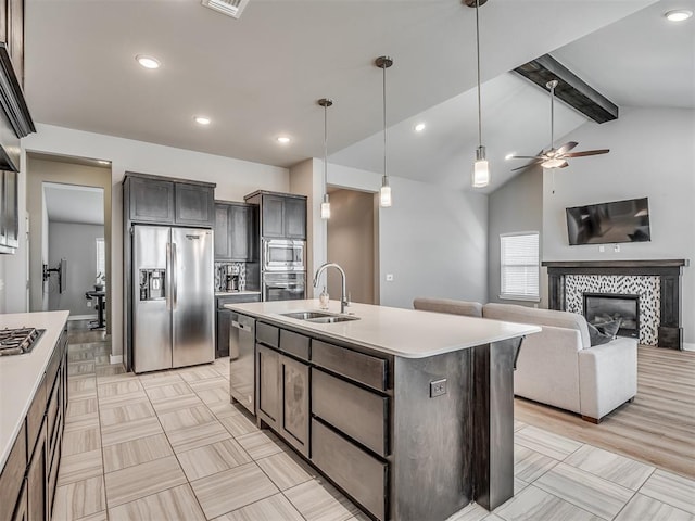 3903 Painted Bird Ln, Norman, OK 73071 - kitchen featuring appliances with stainless steel finishes, a ceiling fan, light countertops, a tiled fireplace, and decorative light fixtures
