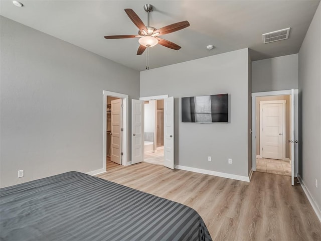 3903 Painted Bird Ln, Norman, OK 73071 - unfurnished bedroom with light wood-style floors, a spacious closet, ensuite bathroom, and ceiling fan