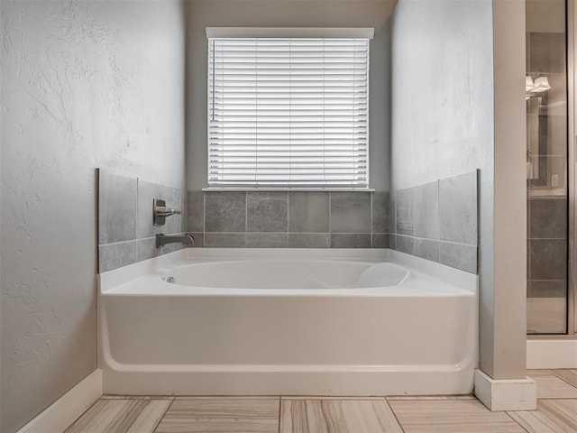 3903 Painted Bird Ln, Norman, OK 73071 - bathroom featuring a bath, a textured wall, and a shower stall