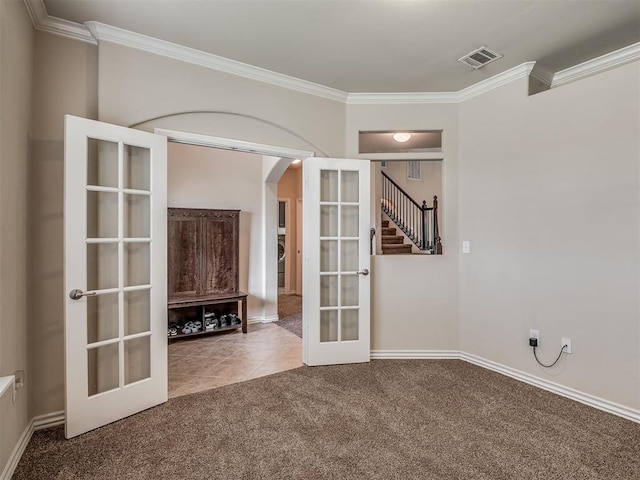 2313 NW 154th St, Edmond, OK 73013 - tiled spare room featuring french doors, crown molding, carpet, arched walkways, and stairway