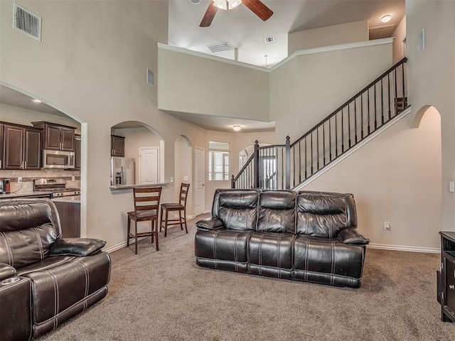 2313 NW 154th St, Edmond, OK 73013 - carpeted living area with arched walkways, ceiling fan, a towering ceiling, and stairs