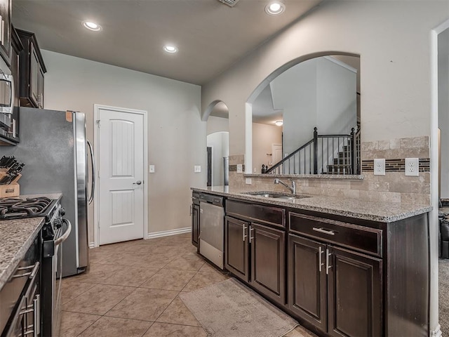 2313 NW 154th St, Edmond, OK 73013 - kitchen with appliances with stainless steel finishes, arched walkways, light stone countertops, backsplash, and recessed lighting
