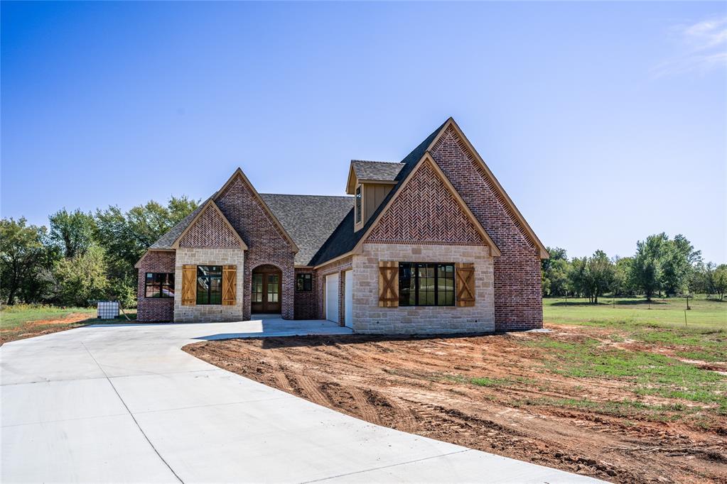3124 Red Ridge Dr, Blanchard, OK 73010 - french provincial home with driveway, an attached garage, stone siding, and brick siding