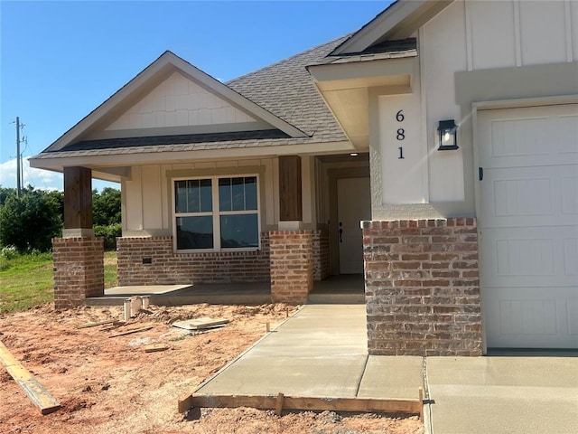 681 Cedar Hill Way, Washington, OK 73093 - doorway to property featuring board and batten siding, a shingled roof, brick siding, and a porch