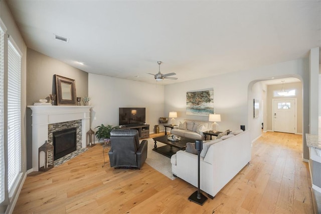6301 Oxnard St, Edmond, OK 73034 - living area with arched walkways, a ceiling fan, light wood-style flooring, and a stone fireplace