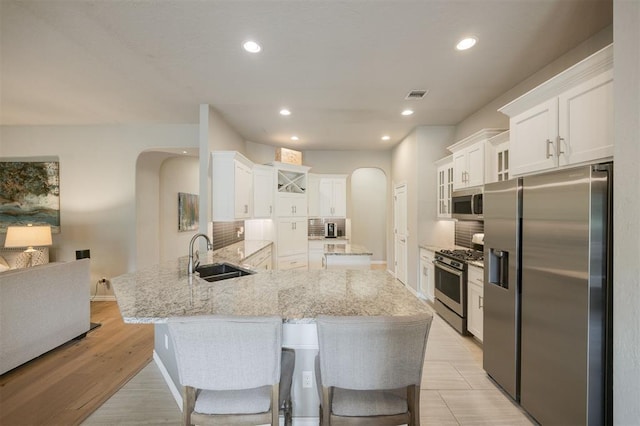 6301 Oxnard St, Edmond, OK 73034 - kitchen featuring appliances with stainless steel finishes, arched walkways, a peninsula, tasteful backsplash, and white cabinets