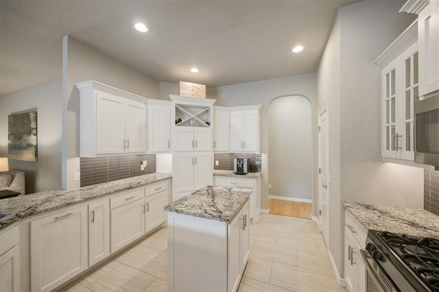 6301 Oxnard St, Edmond, OK 73034 - kitchen with decorative backsplash, white cabinetry, recessed lighting, light stone counters, and a kitchen island