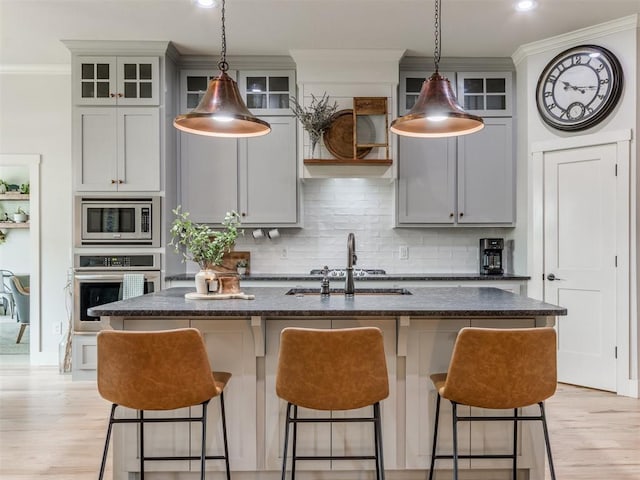 2209 Marjorie Ln, Yukon, OK 73099 - kitchen with stainless steel appliances, ornamental molding, a kitchen bar, a center island with sink, and light wood-style floors