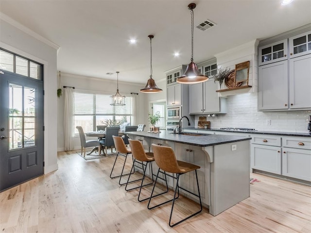 2209 Marjorie Ln, Yukon, OK 73099 - kitchen featuring stainless steel appliances, ornamental molding, a breakfast bar area, decorative backsplash, and a kitchen island with sink