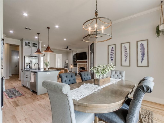 2209 Marjorie Ln, Yukon, OK 73099 - dining area featuring a chandelier, ornamental molding, light wood-style floors, a ceiling fan, and a brick fireplace