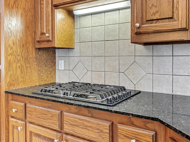 4109 Riva Ridge Ct, Edmond, OK 73003 - kitchen featuring stainless steel gas cooktop, decorative backsplash, brown cabinets, and dark stone counters