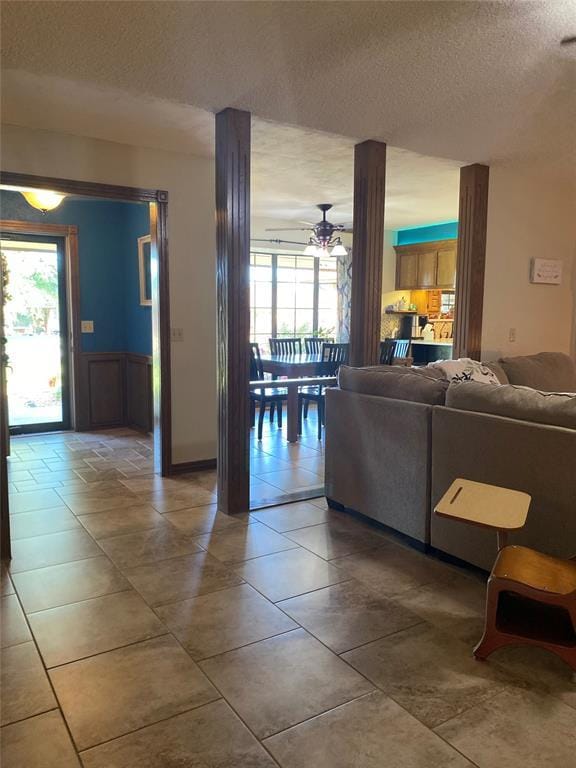 513 9th Street Cir, Hydro, OK 73048 - living area with a textured ceiling, healthy amount of natural light, ceiling fan, wainscoting, and tile patterned floors