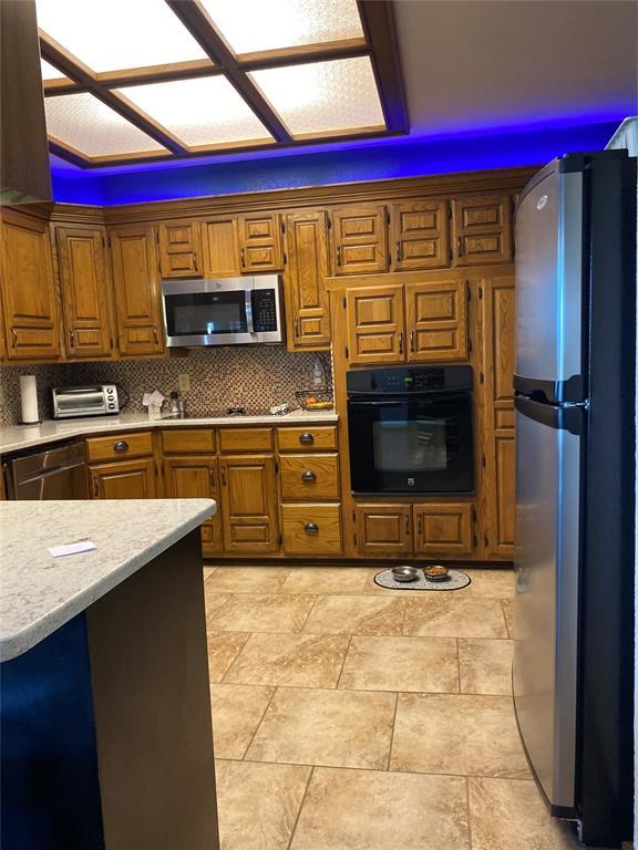 513 9th Street Cir, Hydro, OK 73048 - kitchen with black appliances, brown cabinets, and tasteful backsplash