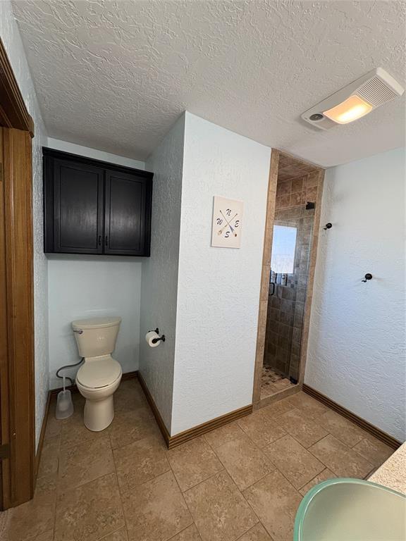 513 9th Street Cir, Hydro, OK 73048 - full bathroom featuring a shower stall, a textured ceiling, and a textured wall