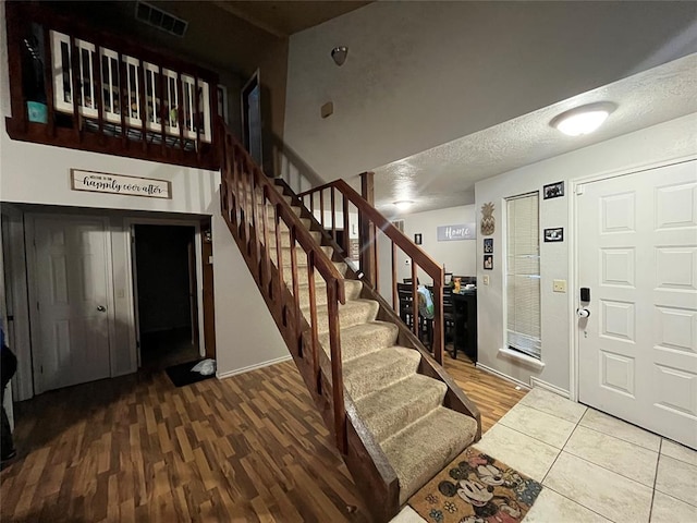 entryway with stairs, wood finished floors, and a textured ceiling