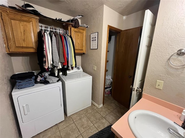 washroom featuring washing machine and dryer, a textured ceiling, a textured wall, and light tile patterned flooring