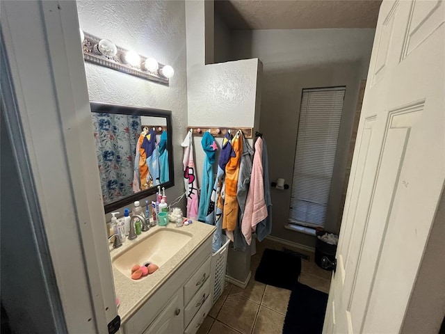 full bathroom with tile patterned floors, vanity, a textured ceiling, and a textured wall