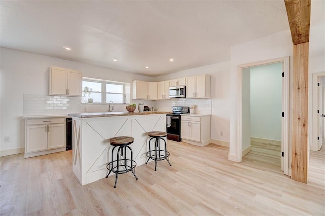 1646 County Road 1245, Tuttle, OK 73089 - kitchen with electric range oven, stainless steel microwave, backsplash, a kitchen bar, and recessed lighting