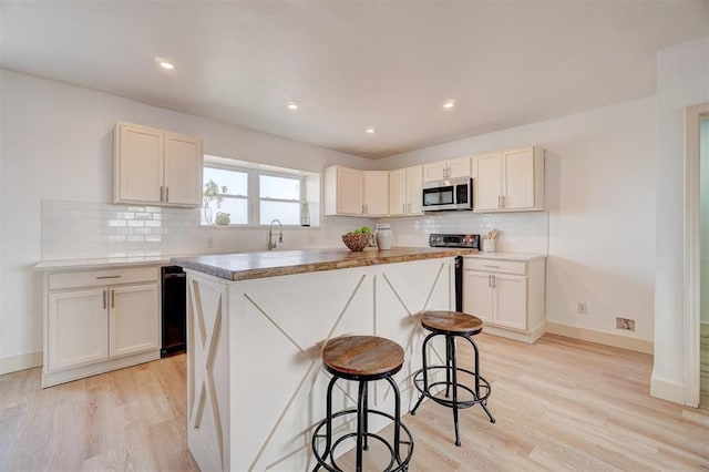 1646 County Road 1245, Tuttle, OK 73089 - kitchen featuring stainless steel microwave, backsplash, light wood-style flooring, a kitchen bar, and recessed lighting