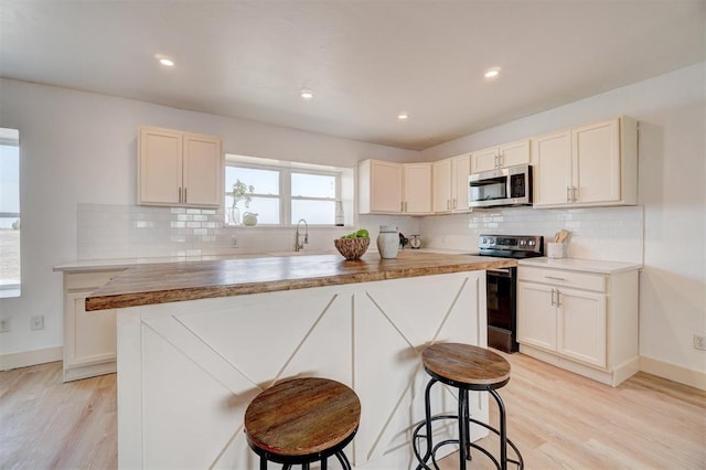 1646 County Road 1245, Tuttle, OK 73089 - kitchen featuring stainless steel appliances, a center island, backsplash, light wood-style floors, and a kitchen bar