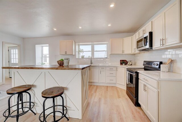 1646 County Road 1245, Tuttle, OK 73089 - kitchen featuring stainless steel microwave, range with electric stovetop, a breakfast bar, plenty of natural light, and recessed lighting