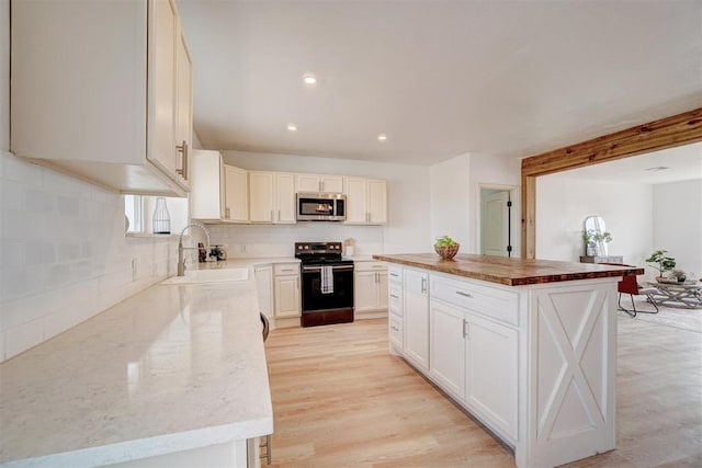 1646 County Road 1245, Tuttle, OK 73089 - kitchen featuring range with electric cooktop, stainless steel microwave, backsplash, a center island, and light wood finished floors