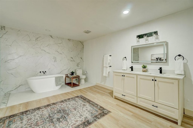 1646 County Road 1245, Tuttle, OK 73089 - bathroom featuring double vanity, a soaking tub, wood finished floors, recessed lighting, and an accent wall