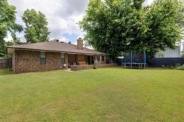410 E Johnson St, Lexington, OK 73051 - rear view of house with a trampoline, a chimney, and brick siding