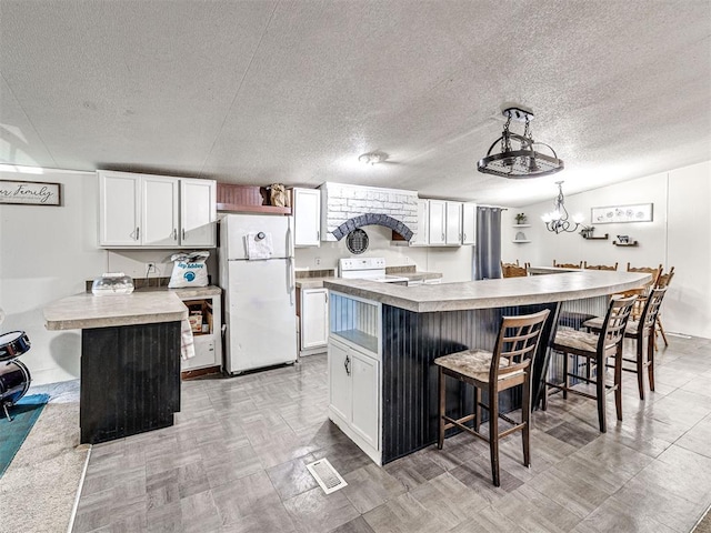 106411 Happy Trails Rd, Mcloud, OK 74851 - kitchen with white appliances, a breakfast bar area, white cabinetry, and a textured ceiling