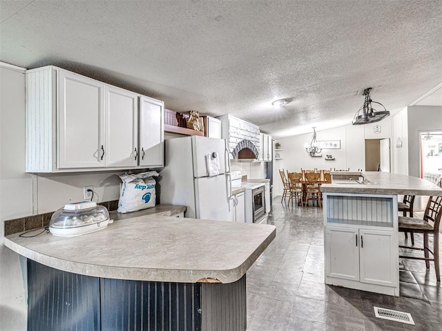 106411 Happy Trails Rd, Mcloud, OK 74851 - kitchen with white appliances, a breakfast bar, a textured ceiling, white cabinetry, and light countertops